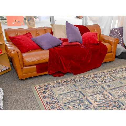 Comfy reading nook with pillows and blanket near book display