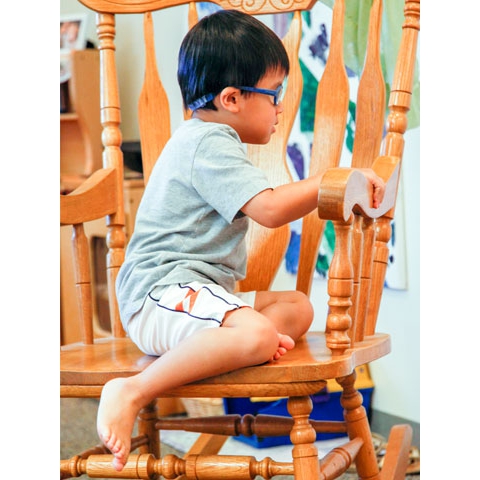 Child with low vision sitting in rocking chair