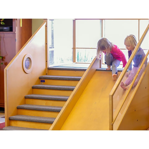 Two children sliding down wood slide