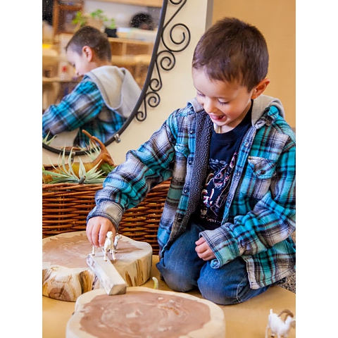 Child playing with toy animals and natural materials