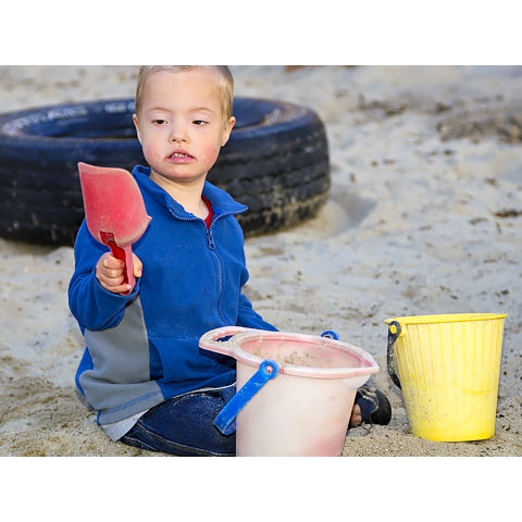 Child in sand with pails and shovel