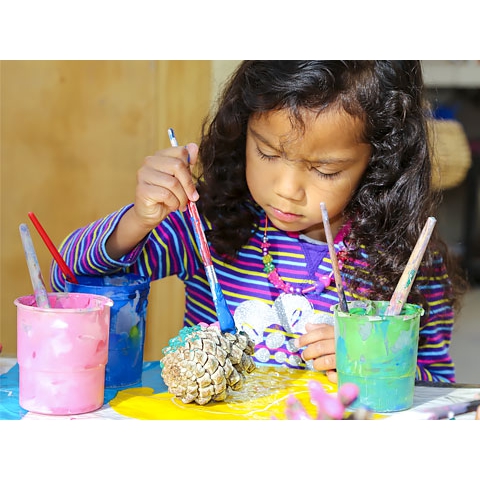 Child painting pine cone